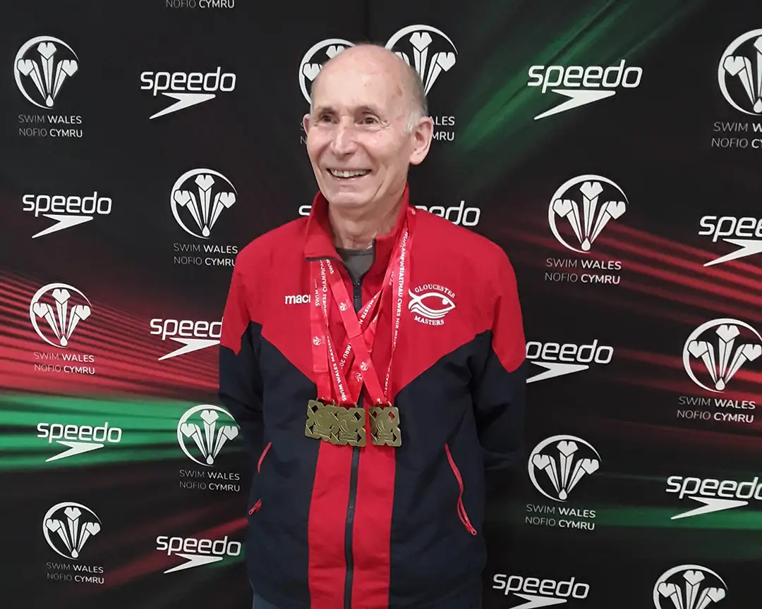 Man standing with three medals around his neck.
